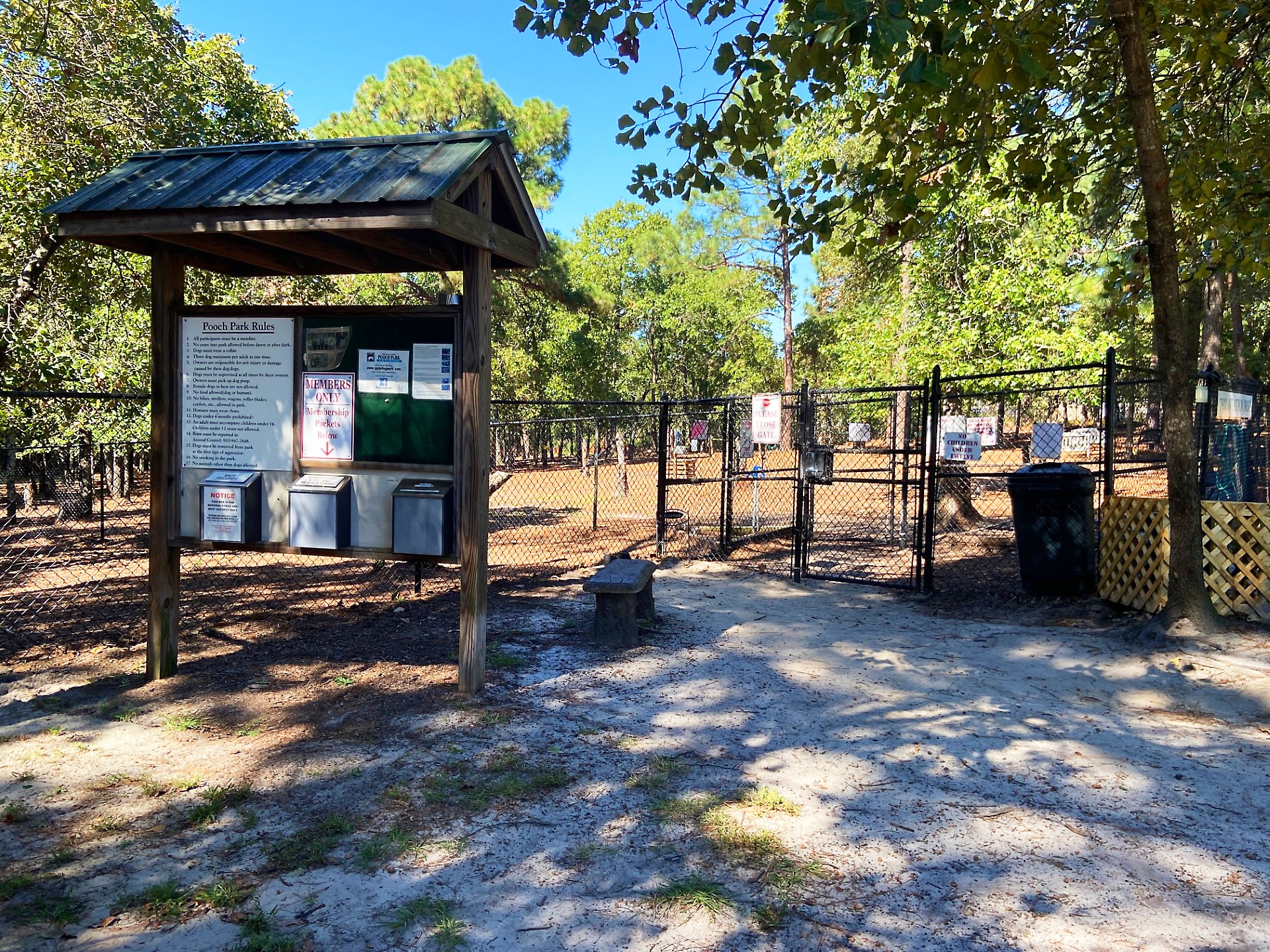 Fenced dog park with shade trees and benches